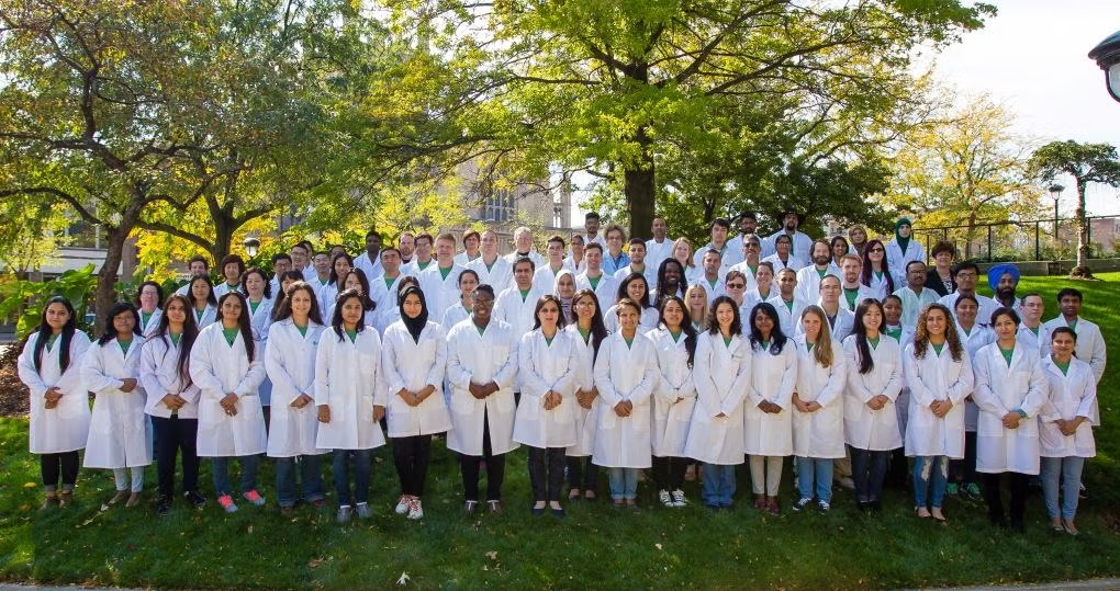 A large group of GRHD members in lab coats posing for group photo on outside lawn.