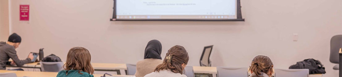 A group of students working on math word problem shown on a whiteboard in a classroom.