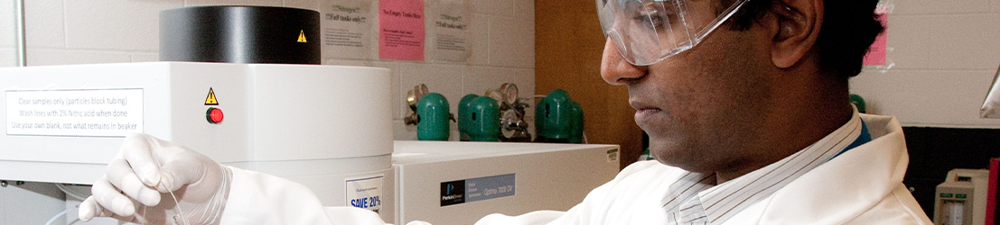 A student handling research equipment in a lab.