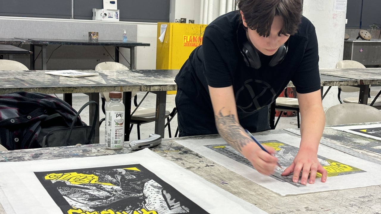 Student trimming print in printmaking studio