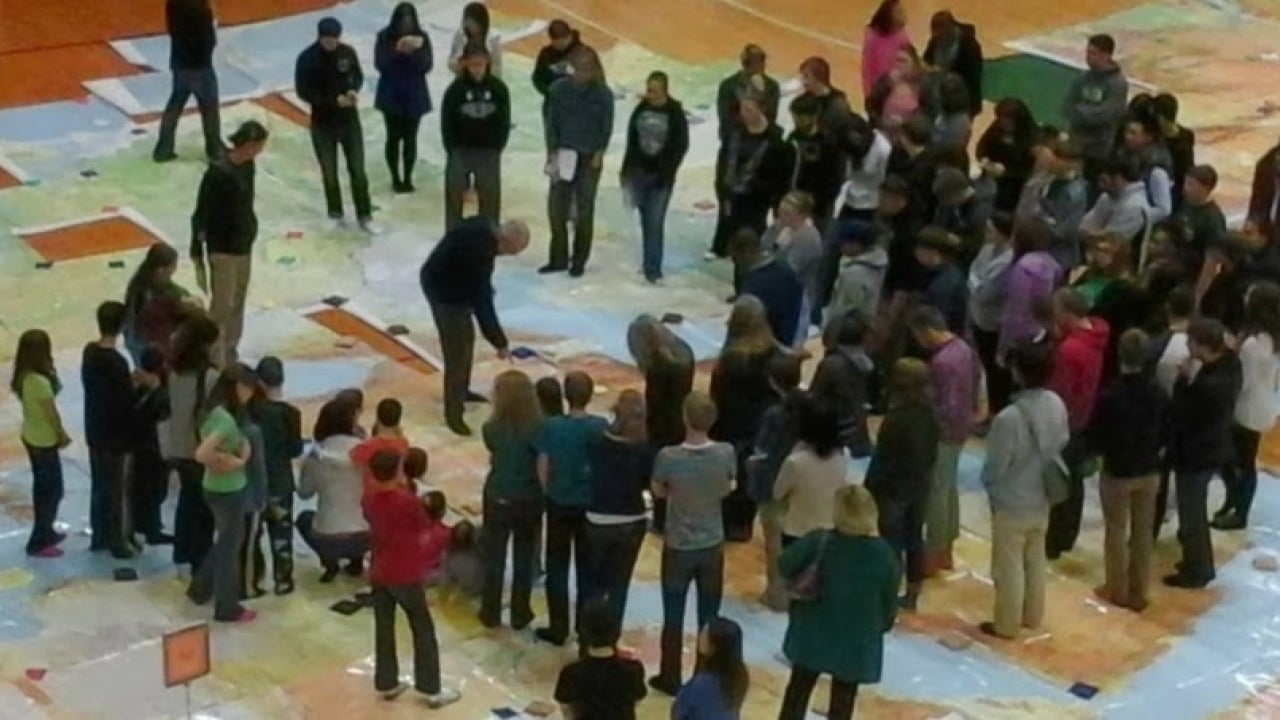 Students standing on a map of the world
