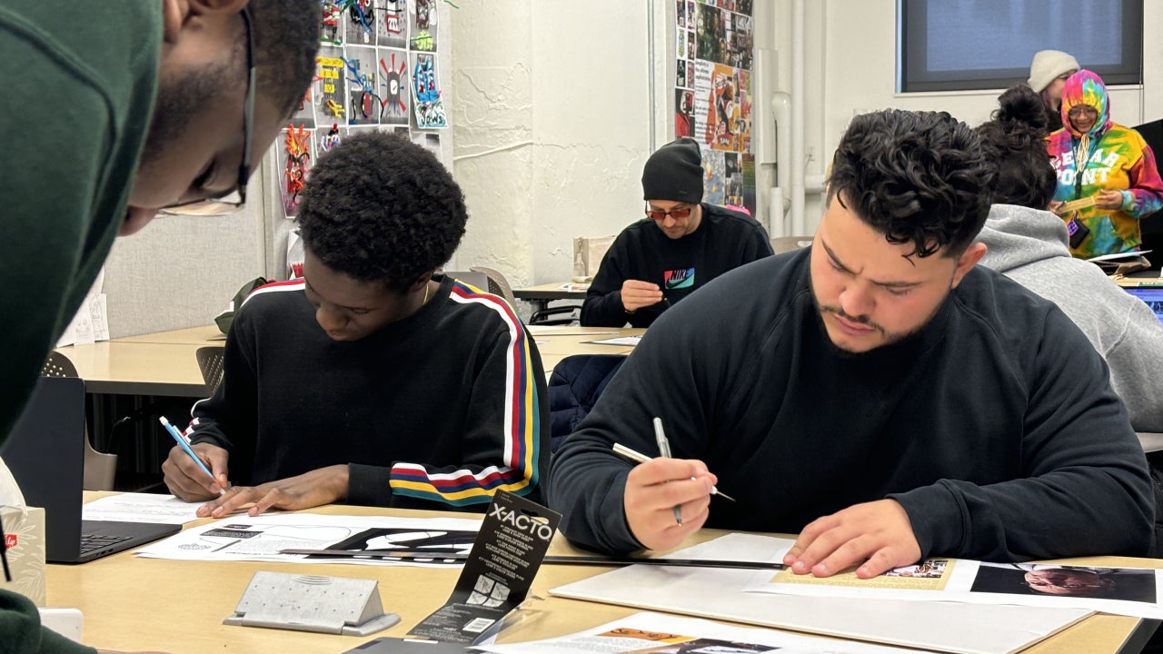 Students working on design projects on a table in a design classroom.