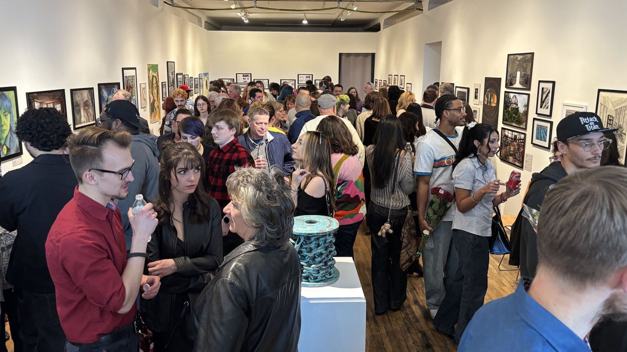 Crowded art gallery at a CSU student art exhibition reception.