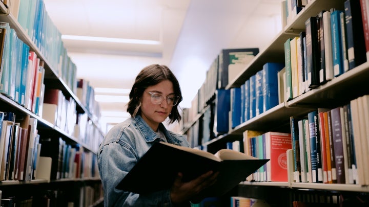 Student in library holding a book