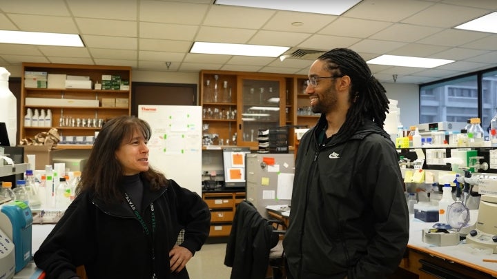 A BIO student and a professor discussing in a well-lit classroom lab.