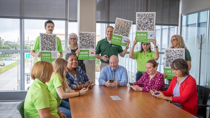College of Engineering administrators holding up signs with QR Codes that link to its Twitter page