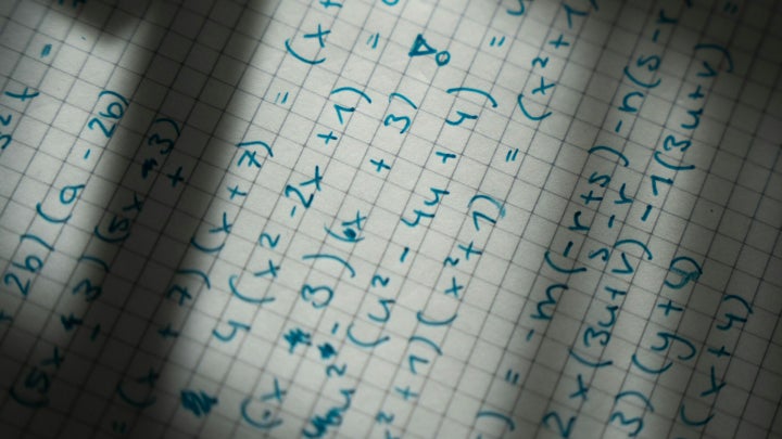 Math homework with equations written in blue ink.