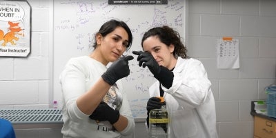 Two BIO students holding and observing a small material in a classroom.