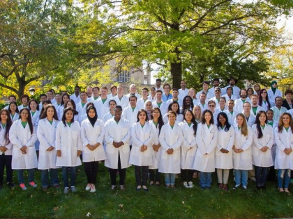 A large group of GRHD members in lab coats posing for group photo on outside lawn.