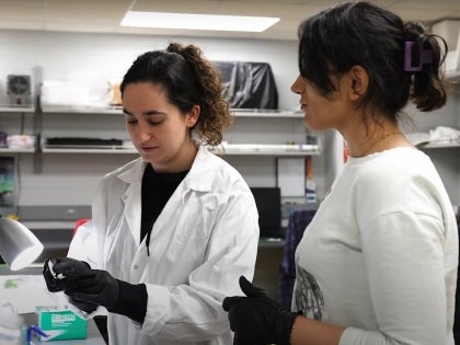 Two EVS students in lab coats conducting research in well-lit laboratory.
