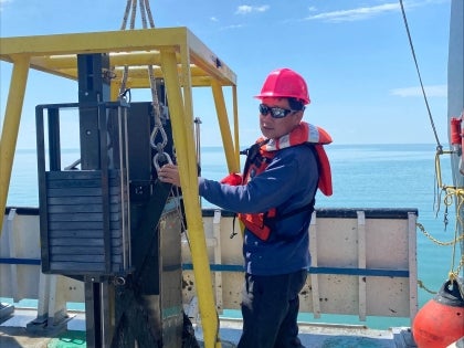 An EVS faculty member in safety gear outside on a boat conducting field research.