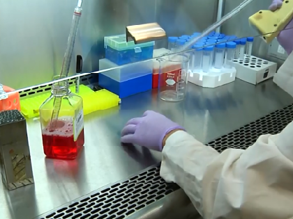 A BIO student in lab coat handling chemical solutions and equipment in a lab.