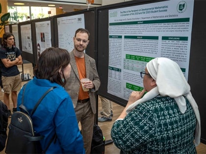Two professors and a student discussing research poster in poster session event at CSU.