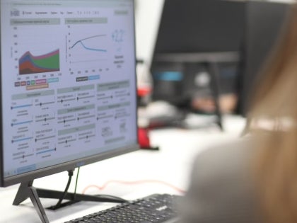 A female student working on data analytics and graphing on a computer monitor in a classroom.