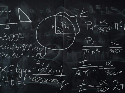 Multiple math equations written with white chalk on a black chalkboard.