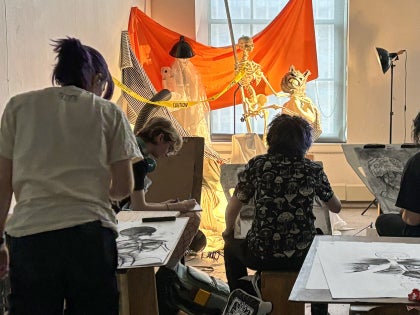 Student artists draw skeletons in a life drawing class.
