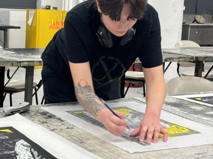 Student trimming print in printmaking studio