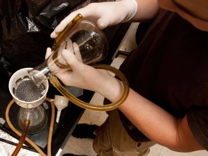 A student pouring chemical liquid into a flask in a lab.