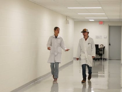 Two students walking and having a conversation in a bright hallway.