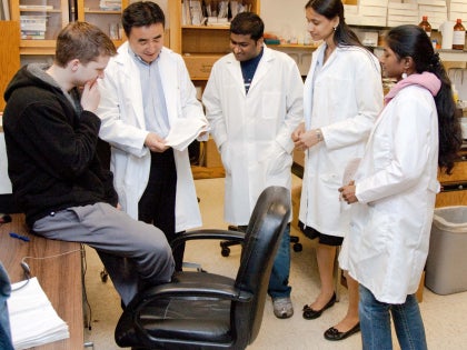 A group of students and a professor having a discussion in a classroom.