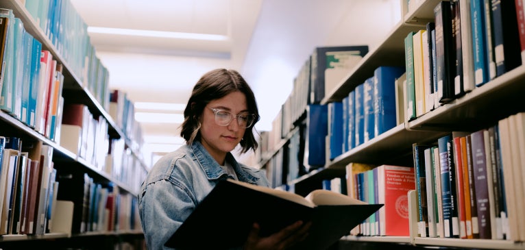 Student in library holding a book